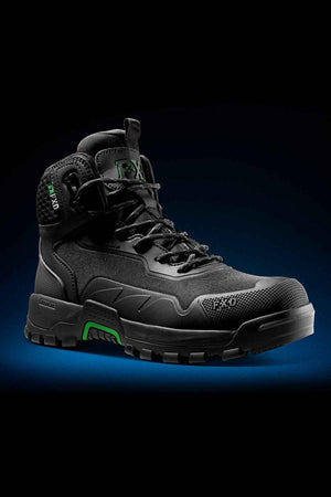 The FXD WB-6 Work Boot, a black high-top with green accents, showcases a rugged design and reinforced toe. It features heavy-duty laces, thick tread for traction, and visible branding. Set against a dark background with a subtle blue gradient, the boot includes an advanced synthetic upper for enhanced durability.