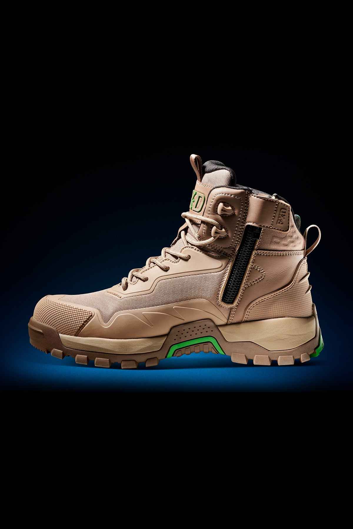 The FXD WB-6 Work Boot is a tan, rugged work boot featuring a high ankle collar, secure lacing system, side zipper for ease of use, and green accents on the sole. Designed to meet safety standards, it boasts a durable and reinforced toe along with a textured tread for superior grip. Enhanced comfort is provided by a PORON heel insert. The product image is set against a dark background with a subtle blue gradient.