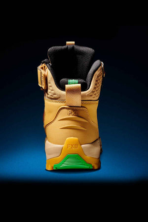 A single FXD WB-6 Work Boot in tan is depicted from the back against a dark background. The boot showcases diverse textures and stitching, includes a black padded collar, and features a sole with orange and green accents. The brand name "FXD" is prominently imprinted on the heel. For added comfort, it has a Poron heel insert.