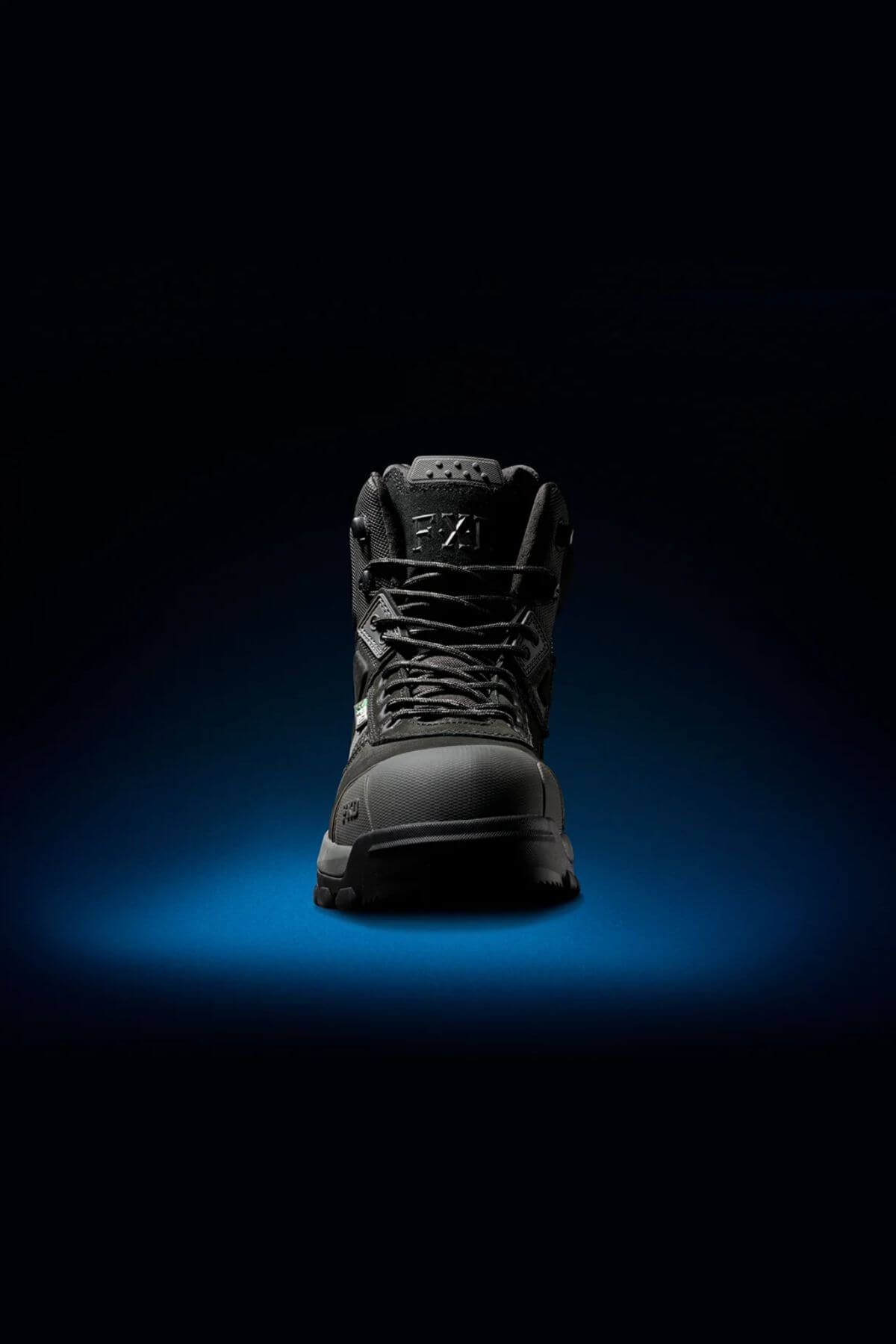 The FXD WB-1 Work Boot is prominently displayed against a dark background with a subtle blue gradient beneath, highlighting its contours and details. The boot appears modern and robust, designed for performance and durability, enhanced with a safety toe for added protection.