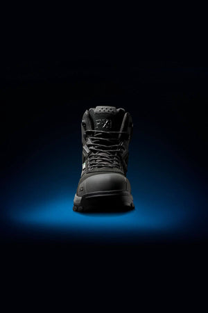 The FXD WB-1 Work Boot is prominently displayed against a dark background with a subtle blue gradient beneath, highlighting its contours and details. The boot appears modern and robust, designed for performance and durability, enhanced with a safety toe for added protection.