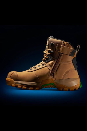 The FXD WB-1 Work Boot, shown individually against a black background with a blue gradient at the bottom, boasts a rugged tan design. It features a safety toe, side zipper, slip-resistant sturdy soles, and reinforced stitching that all suggest durability.
