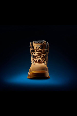 A single FXD WB-1 Work Boot in tan, featuring laces and positioned upright against a dark background with blue lighting beneath. The text "FXD" is visible on the boot's tongue. This rugged work boot, equipped with a safety toe, seems designed for heavy-duty use.