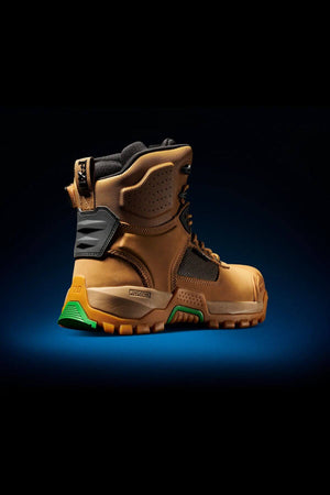 The FXD WB-1 Work Boot, a rugged tan-colored work boot with black and green accents, is displayed against a dark background. This slip-resistant boot boasts a thick, textured sole, reinforced ankle support, and sturdy laces, designed for heavy-duty use and durability.