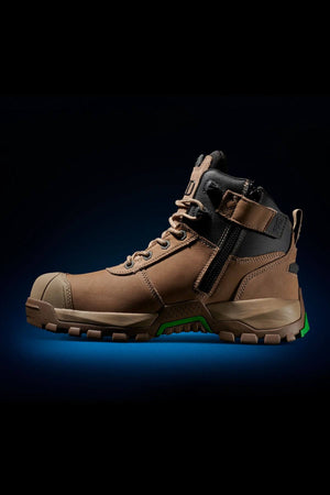 A single FXD WB-2 Work Boot in brown, featuring a sturdy slip-resistant sole, lace-up front, and safety toe, displayed against a black background with a subtle blue glow underneath. The boot showcases reinforced toe and heel areas and green accents on the sole.