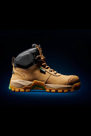 The FXD WB-2 Work Boot, featuring a rugged brown and black design with sturdy, slip-resistant soles, is showcased against a black background accented by a subtle blue glow. The boot includes black ankle padding, metal eyelets for laces, and a reinforced safety toe area.