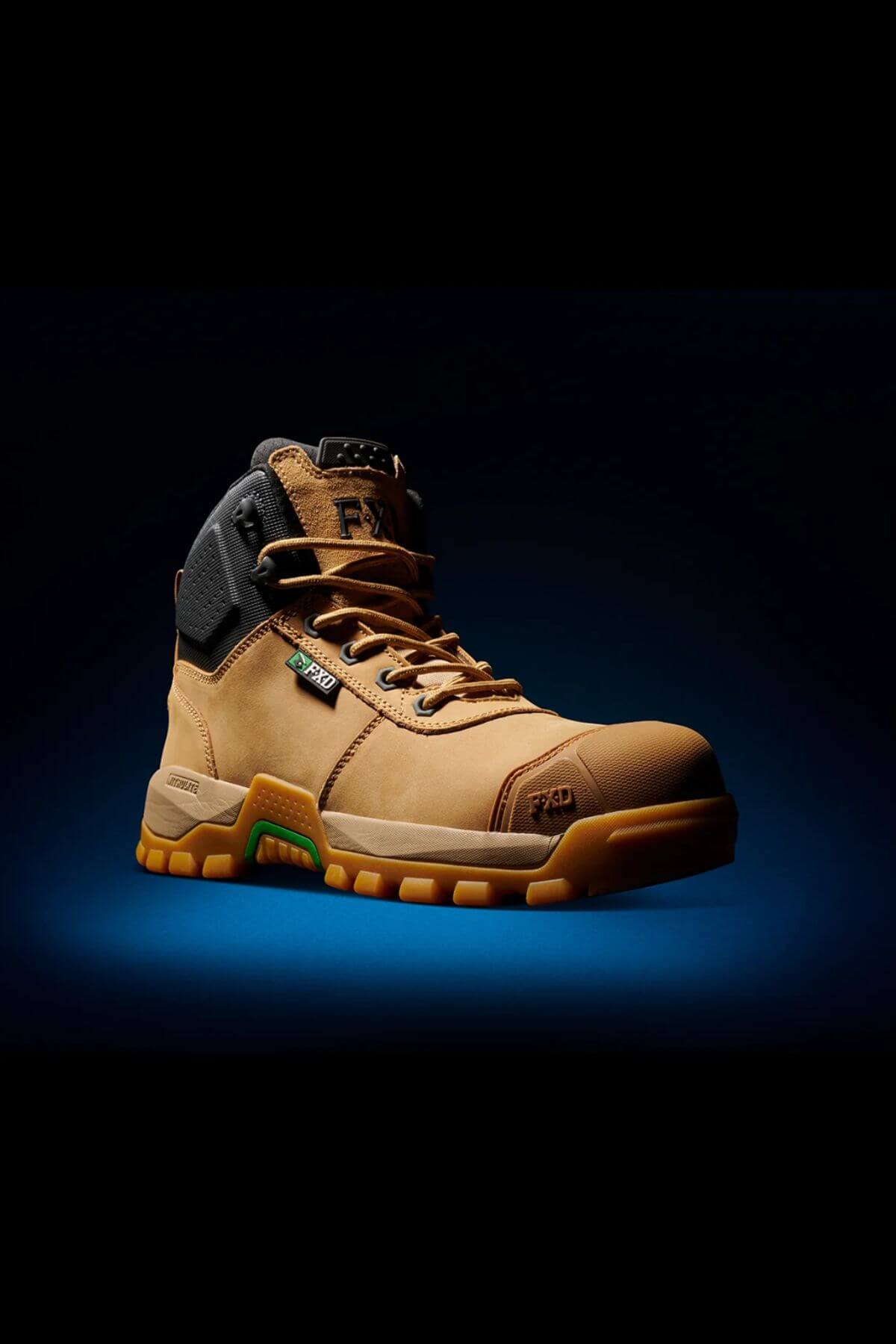 A single FXD WB-2 Work Boot, tan in color with a black padded collar, is displayed against a dark backdrop. The boot boasts a robust, slip-resistant sole with green accents and laces. It features safety toe reinforcement and includes logos and text highlighting its design for performance and safety.