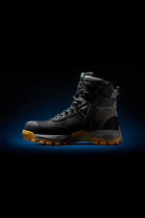The FXD WB-1 Work Boot in black, featuring a high ankle with green accents and a thick, rugged yellow sole. This boot includes metal eyelets, a side zipper, and reinforced areas for enhanced durability. Additionally, it boasts NITROLITE midsole cushioning for added comfort. The backdrop is black with a subtle blue gradient halo surrounding the boot.