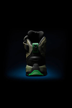 The FXD WB-2 Work Boot is shown from the back, highlighting black and green accents, a side buckle, rugged sole, and NITROLITE midsole cushioning, set against a dark background with a blue spotlight beneath.