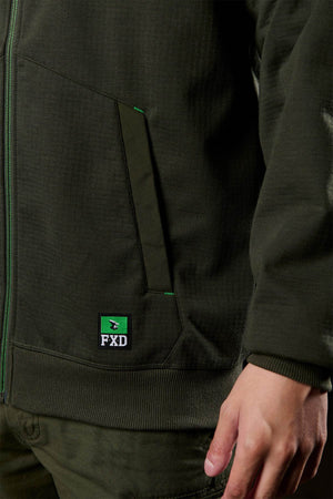 A person wearing a dark green FXD WF-3 Jacket and matching pants, with their right hand by their side. The jacket features a front pocket, an FXD logo patch near the pocket, and water-resistant design.