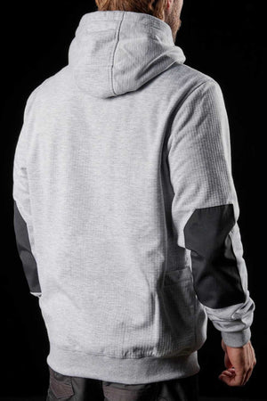 A person with light brown hair is shown from behind, wearing the grey FXD WF-1 Hoodie with the hood up and black elbow patches. The hoodie's texture appears soft, slightly ribbed, and windproof fleece. The background is black.