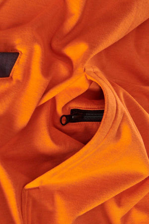 A close-up of the FXD WF-1 Hoodie's orange fabric features a partially open black zipper. The material, resembling water-resistant fleece, displays some folds and creases around the zippered pocket.