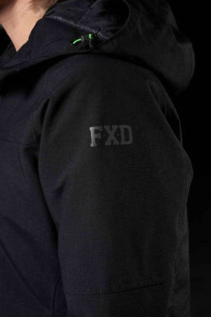 A close-up of someone wearing the FXD WO-1W Womens Insulated Work Jacket in black, featuring “FXD” in gray on the upper arm. The background is black and the person’s face isn’t visible.