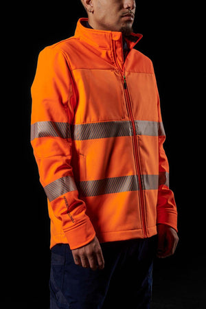 A person wearing a bright orange FXD WO-3T Hi Vis Soft Shell Work Jacket, designed with reflective horizontal stripes, stands against a dark background. They are shown from the chest up, with their arms slightly bent at the elbows. The breathable wind and water-resistant jacket features a high collar and a zippered front.