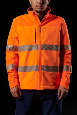 A person wearing the FXD WO-3T Hi Vis Soft Shell Work Jacket, featuring bright orange fabric and reflective silver stripes across the chest and arms. The 3-layer polyester softshell jacket is zipped up, breathable, and wind and water-resistant as the person stands against a dark background with their hands resting at their sides.