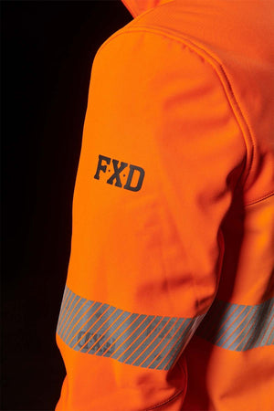 Close-up of a person wearing the FXD WO-3T Hi Vis Soft Shell Work Jacket in bright orange with reflective stripes around the arm. Crafted from a 3-layer polyester softshell, this breathable, wind and water-resistant jacket features "FXD" printed in black on the upper sleeve. The dark background highlights its vivid color.