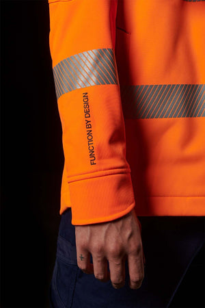 A person wearing an FXD WO-3T Hi Vis Soft Shell Work Jacket with reflective stripes stands against a black background. Featuring a durable water repellent finish, the jacket's sleeve boasts "FUNCTION BY DESIGN" in bold print. The person has a small cross tattoo on their index finger.