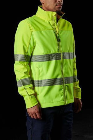 Standing against a black background, a person wears an FXD WO-3T Hi Vis Soft Shell Work Jacket in bright yellow-green with reflective silver bands on the chest and arms. The jacket is wind and water-resistant, zipped up for comfort and safety, and offers UPF protection.