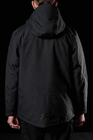 A person stands facing away from the camera wearing the FXD WO-1 Insulated Work Jacket—black, wind and water resistant, with reflective details, subtle seams, a relaxed fit—and matching black pants against a dark background.