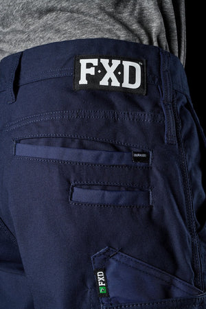 Close-up of the back pocket of a pair of FXD WP-3T navy blue work pants with reinforced stitching. A black and white "FXD" logo is prominently displayed above the pocket, and a small "DURASC" tag is visible near the seam. The durable, heavy-duty fabric features 360-degree stretch for added flexibility.