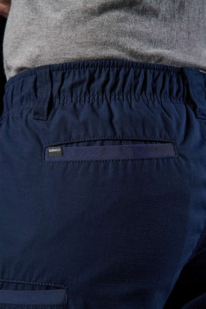 Close-up of someone wearing navy blue FXD WS-7 Work Shorts featuring an elastic waistband, ideal for work with a focus on durability and comfort. The textured fabric pattern is complemented by a small "Durango" label. Paired with the shorts is a grey top.