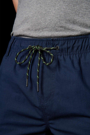 A person wearing the FXD WS-7 Work Short featuring navy blue color and a sturdy black and green drawstring at the waist, paired with a gray shirt for ultimate comfort.