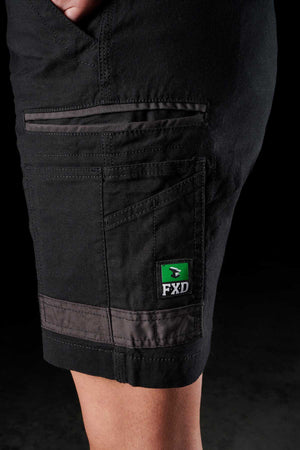 A person wearing the FXD Womens WS-3W Short in black, featuring stretch material and DURA500 reinforced pockets, with a visible green and black FXD logo on the side pocket. The shorts look durable and designed for practical use.