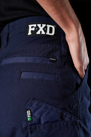 Close-up of a person wearing navy blue FXD Womens WS-3W Shorts. The shorts feature DURA500 reinforced pockets and triple needle seams, including a visible FXD label on both the waistband and a side pocket. The person's hand is partially visible, resting on their hip.