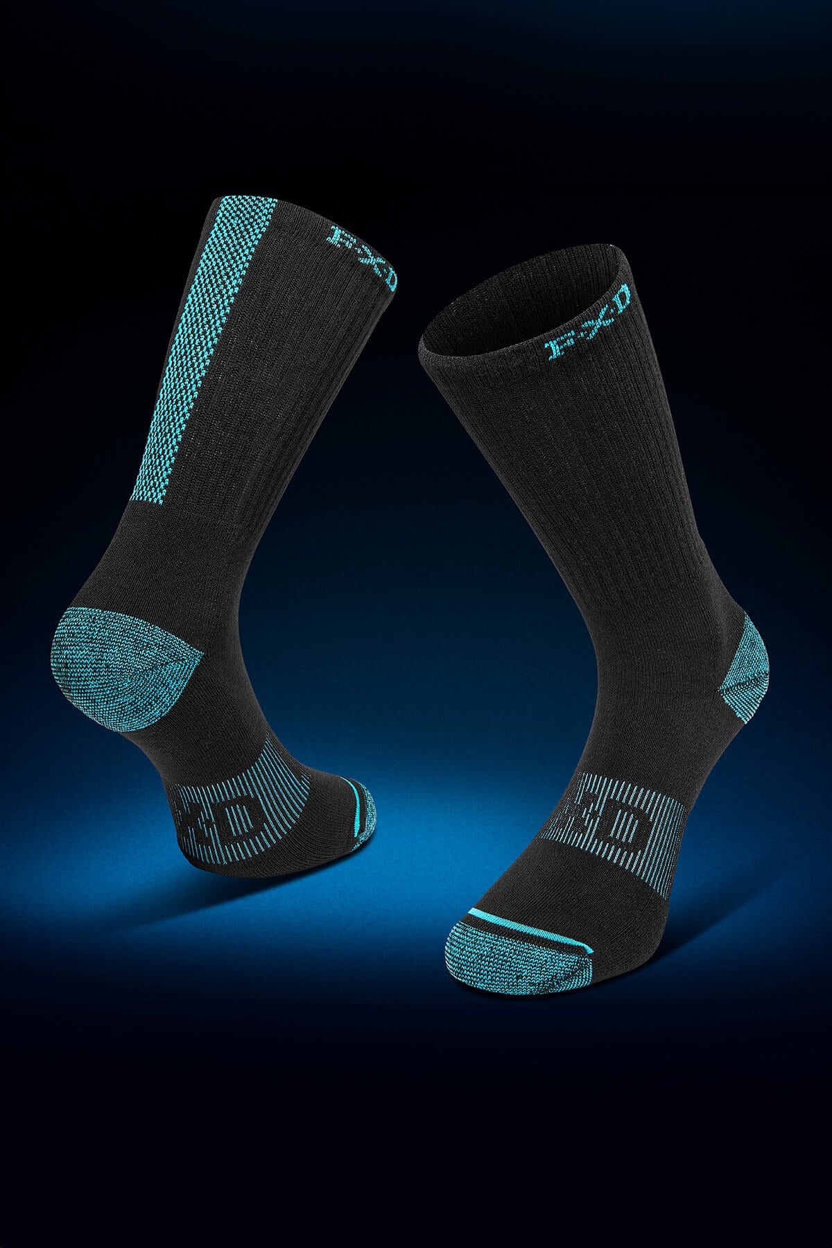 A pair of black FXD SK-8W Crew Socks from the 5-pack collection with turquoise accents and a jacquard logo is displayed against a dark gradient background. Featuring ribbed texture, padded foot bed, and reinforced toe and heel areas, one sock stands upright while the other is slightly tilted.
