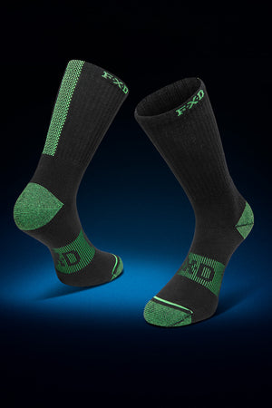 A pair of black and green FXD SK-8W Crew Socks from the 5-pack set are displayed against a dark gradient background. The socks feature reinforced heels, toes, and arch areas with green detailing and patterns. A jacquard logo and text in green decorate the upper part of the socks, complemented by a padded footbed for extra comfort.