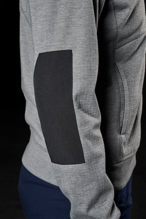 A close-up view of a person wearing a grey sweatshirt with a black elbow patch, showcases the textured fabric of the sleeve against a dark background. The visible pocket seams evoke the design of the FXD Womens WF-3W Jacket, renowned for its water resistance and windproof qualities.