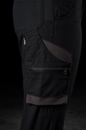 Close-up of a black, rugged FXD Womens WP-7W work pant with multiple pockets, including a zippered pocket and a smaller patch pocket. There is a green and white tag labeled "PRO" stitched near the top pocket. The stitching details, durable fabric, and flex double weave for 50+ UPF protection are visible.