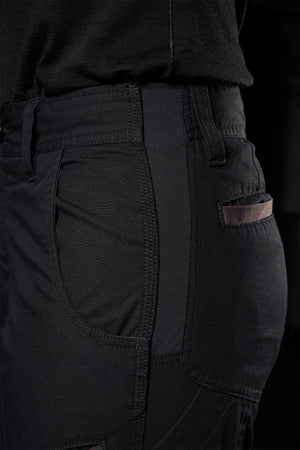 Close-up of a person wearing FXD Womens WP-7W pants, with the focus on the side pocket and part of the leg. The pants have a sleek design with visible stitching and slightly textured fabric, offering flex double weave for comfort. The person is also wearing a dark top tucked into the pants.