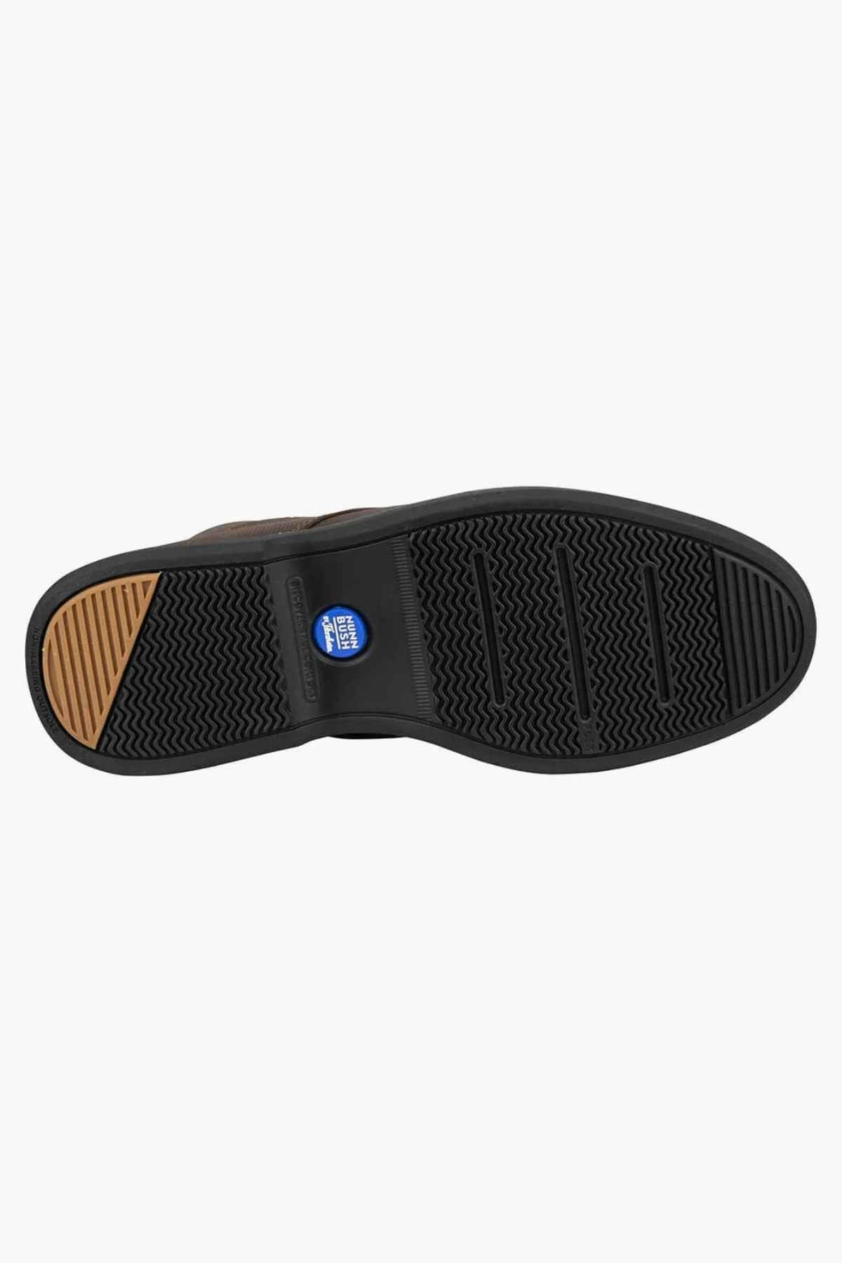 The bottom view of the Florsheim Otto Chukka Boot shows a black sole with textured patterns, horizontal grooves, and chevron designs near the toe. A circular blue logo is in the arch area, enhancing its leather upper and cushioned footbed for maximum comfort.