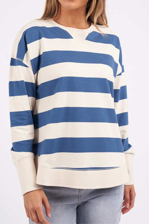 A woman wears the Foxwood Delilah Stripe Crew, a cream and blue striped cotton jumper, with light-wash jeans. The image is cropped at her nose and upper thighs against a plain light background.