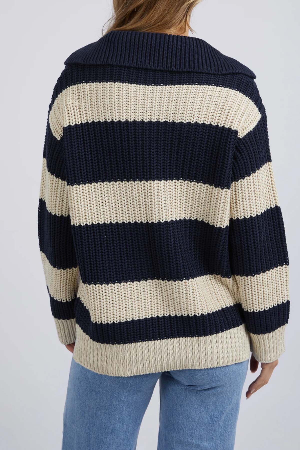 A person is shown from the back wearing the Foxwood Estella Stripe Knit, featuring chunky yarn-dyed stripes and a wide collar, paired with light blue jeans.