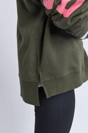 A person in the Foxwood Interval Hoodie (dark green, side slits) paired with black pants, shown waist-down on a light background—ideal for everyday wear.