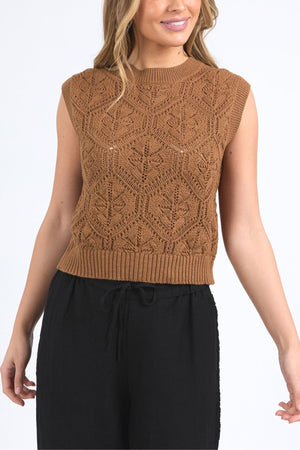 A woman wearing the Foxwood Luna Knit Vest—a sleeveless brown pointelle top with a geometric pattern—and black drawstring pants, standing against a plain white background.
