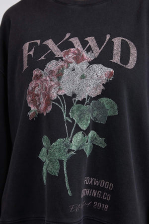 The Foxwood Rosa Crew is a black, 100% cotton sweatshirt featuring an embroidered "FXWD" chest print above a colorful floral graphic, with "FOXWOOD NOTHING CO" and "Est. 2018" elegantly displayed at the bottom.