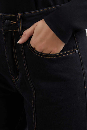 A person is shown wearing Foxwood Royal Wide Leg Jeans, which have contrasting brown stitching and metal rivets, with their right hand in the front pocket. They also sport a long-sleeved black top.