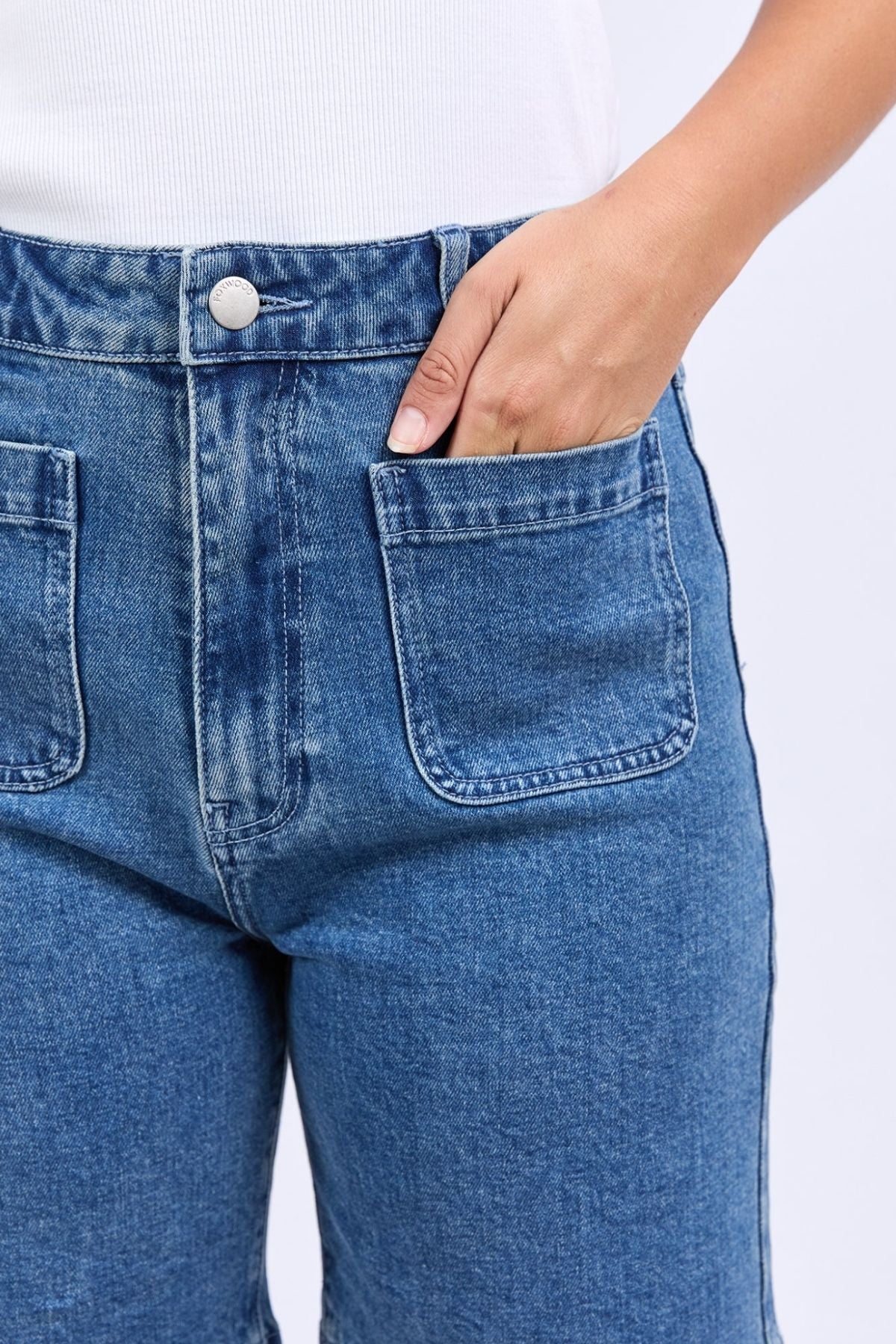 Close-up of a person wearing Foxwood Sarah Short with front patch pockets and a white ribbed top, right hand inside the pocket.
