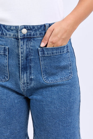 Close-up of a person wearing Foxwood Sarah Short with front patch pockets and a white ribbed top, right hand inside the pocket.