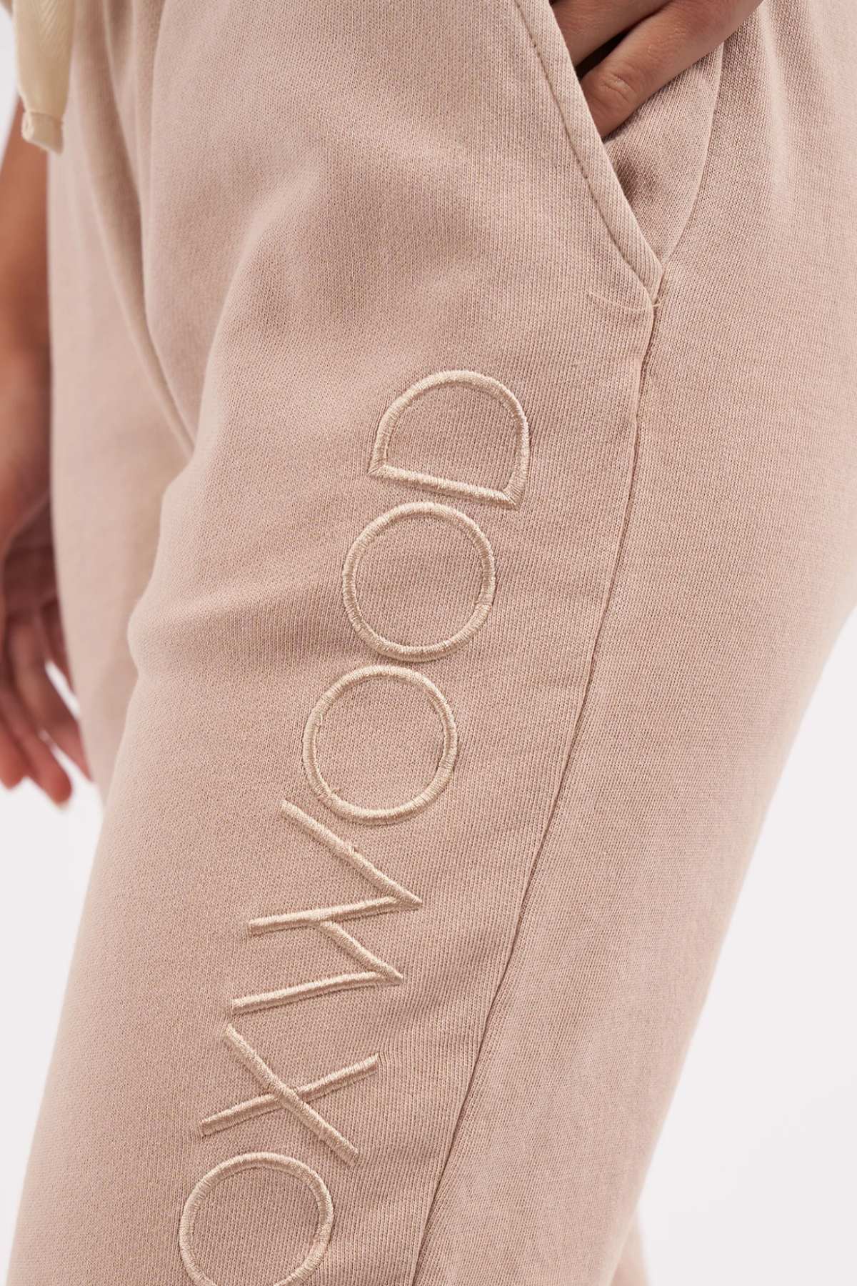 Foxwood Simplified Pant - Oatmeal. Close up image of Foxwood logo embroidery on pants on model