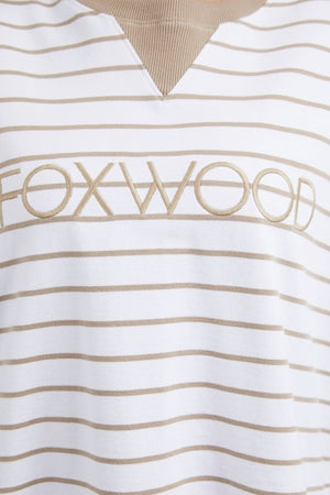 Close-up of the Foxwood Simplified Stripe Crew, a white and beige striped shirt with a V-neck, showcasing yarn dye stripes. The word "FOXWOOD" is elegantly embroidered in beige across the chest, capturing the effortless style of Foxwood Clothing.