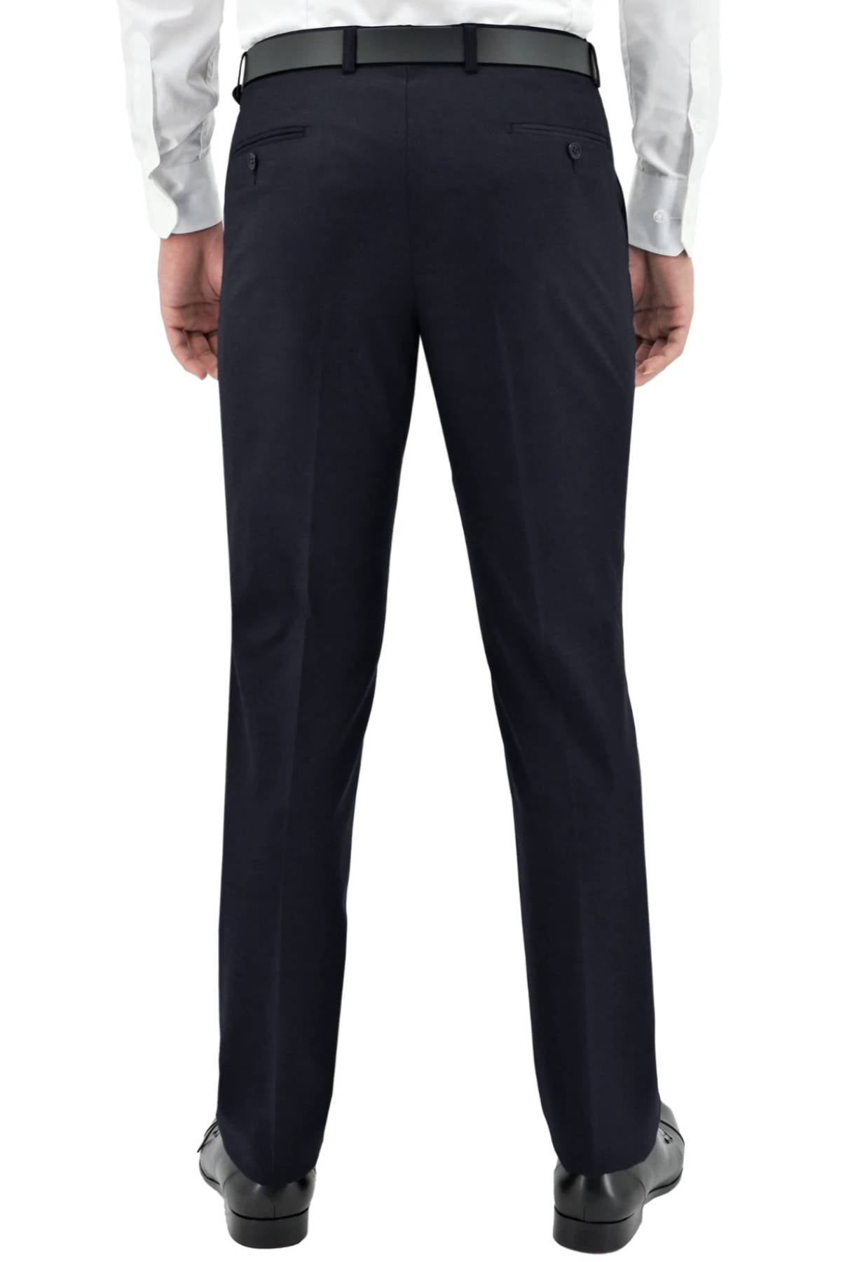 A man stands with his back to the camera, hands relaxed by his sides, wearing a white dress shirt, black belt, and the comfy-fit Boston Lyon Trouser.