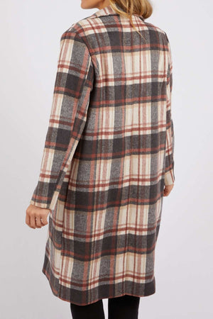 A person stands with their back to the camera, wearing a long Foxwood Westward Coat in cream, gray, and rust check, against a plain white background.