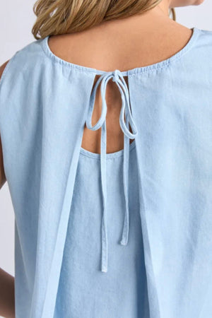 A close-up of a person wearing the Foxwood Zetta Top, a sleeveless chambray style featuring a round neckline and back keyhole with two fabric tie strings, perfect for effortless summer style.