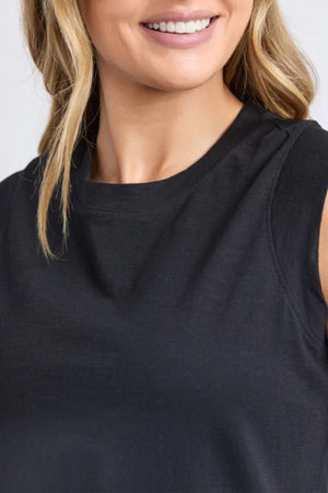 A woman with wavy blonde hair smiles in a sleeveless black top reminiscent of the Foxwood Reform Dress. The photo is cropped at her shoulders and above her nose.