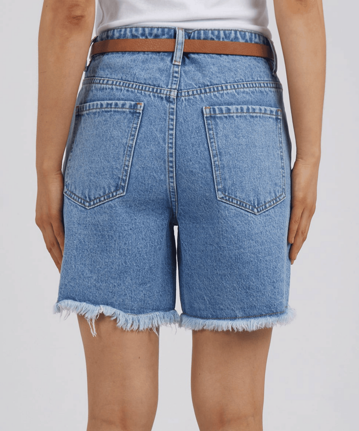 A rear view showcases a person in Foxwood Millie Shorts with a frayed hem and brown belt, perfectly paired with a white top for effortless everyday wear.