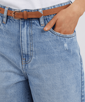 Wearing the Foxwood Millie Short in light blue with a brown belt and white shirt, one hand in the pocket, creates a relaxed vibe akin to classic frayed-hem denim shorts.